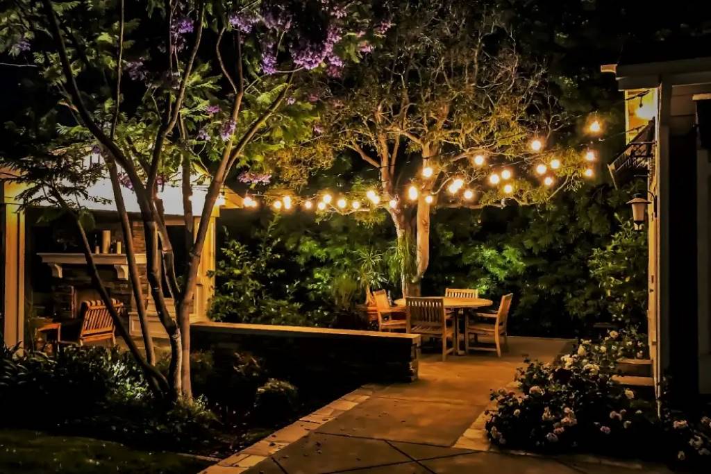 Backyard patio glowing with remote-controlled LED rope lights outlining railings at dusk.